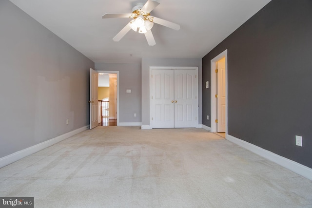 unfurnished bedroom with light carpet, ceiling fan, and a closet