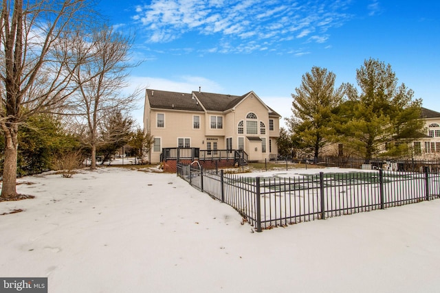 snow covered back of property with a wooden deck