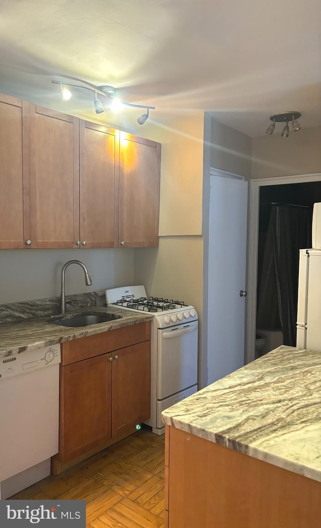 kitchen featuring light stone countertops, white appliances, sink, and light parquet flooring