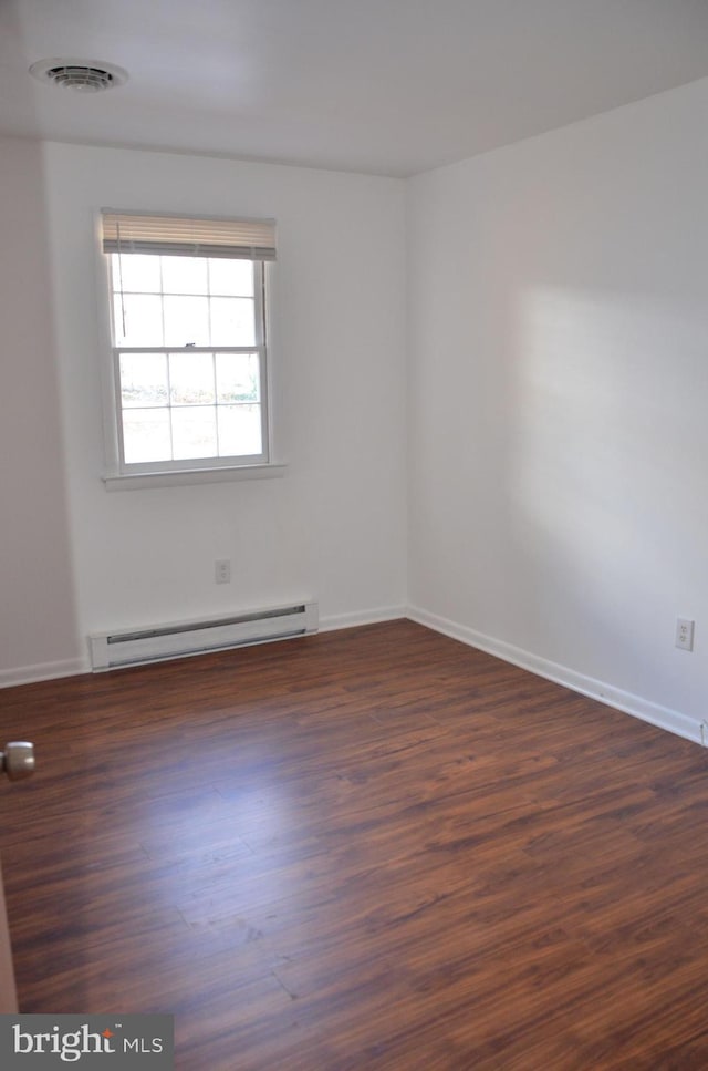 empty room with dark hardwood / wood-style flooring and a baseboard radiator