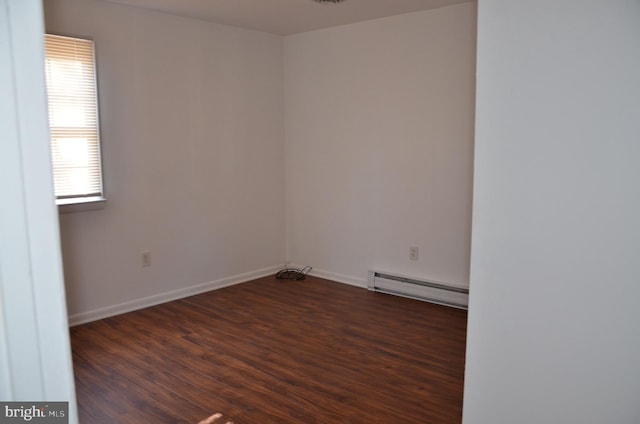 empty room with dark hardwood / wood-style floors and a baseboard heating unit