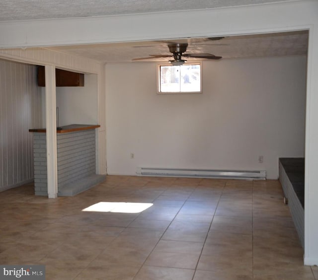 spare room with wooden walls, indoor bar, ceiling fan, baseboard heating, and a textured ceiling