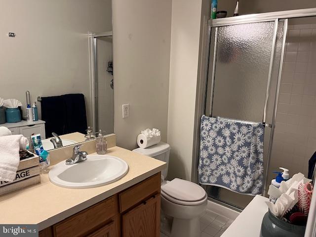 bathroom with tile patterned flooring, vanity, toilet, and walk in shower