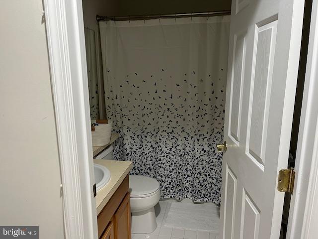 bathroom with tile patterned floors, a shower with curtain, vanity, and toilet