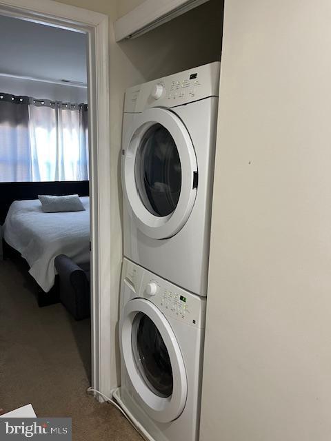 laundry room featuring carpet and stacked washer / dryer