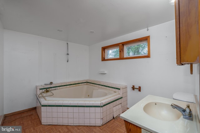 bathroom featuring tiled bath, sink, and parquet floors