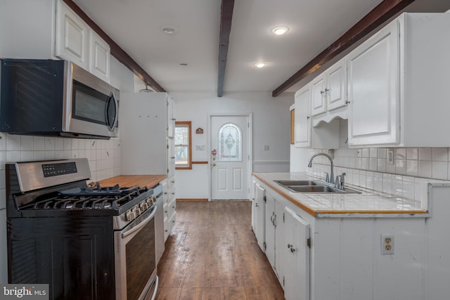 kitchen featuring beam ceiling, white cabinetry, tile countertops, wood-type flooring, and appliances with stainless steel finishes