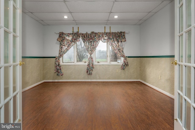 spare room with a paneled ceiling and hardwood / wood-style flooring