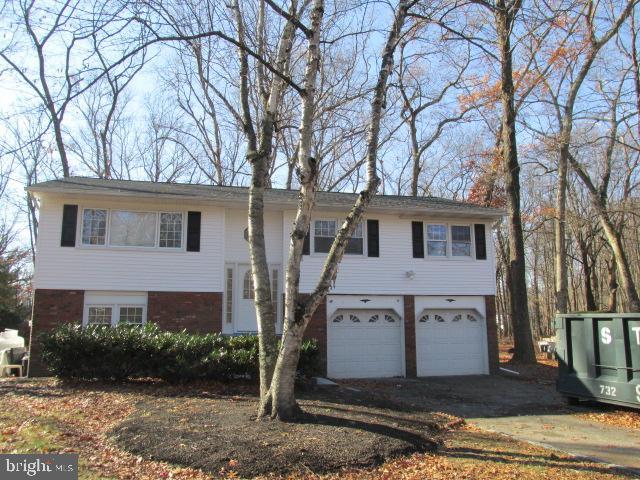 raised ranch with a garage, driveway, and brick siding