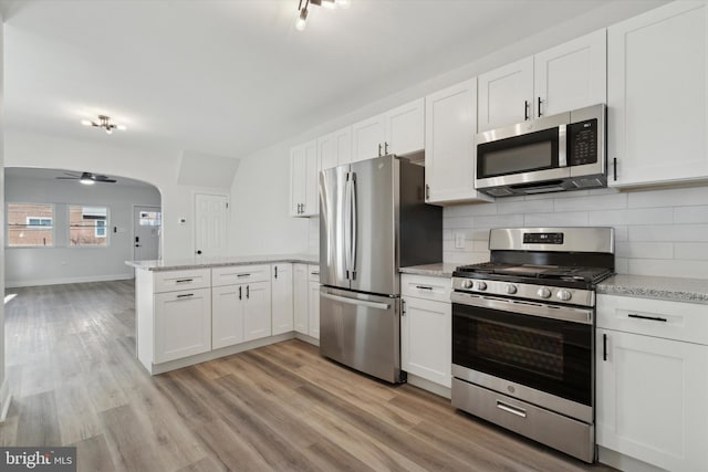 kitchen featuring appliances with stainless steel finishes, backsplash, ceiling fan, light hardwood / wood-style floors, and white cabinetry