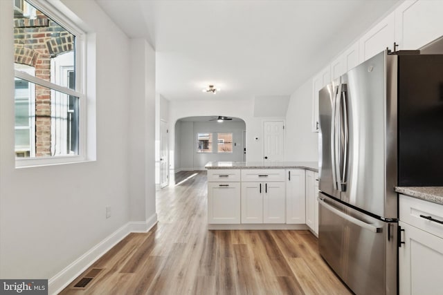 kitchen featuring stainless steel refrigerator, white cabinetry, ceiling fan, and light hardwood / wood-style floors