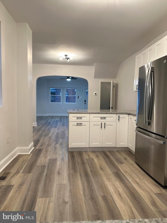 kitchen featuring dark hardwood / wood-style flooring, light stone counters, ceiling fan, white cabinetry, and stainless steel refrigerator