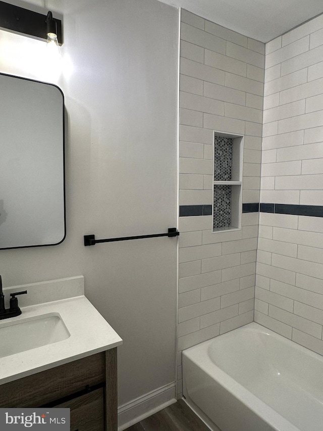 bathroom featuring hardwood / wood-style floors, vanity, and tiled shower / bath