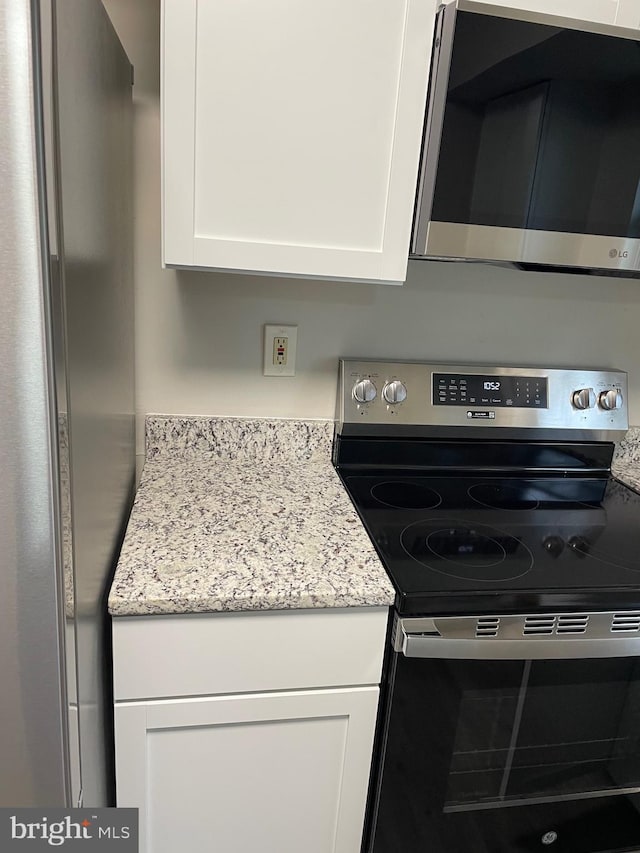 kitchen featuring white cabinets, light stone countertops, and stainless steel appliances