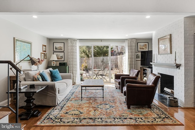 living room with hardwood / wood-style flooring, a brick fireplace, and a healthy amount of sunlight