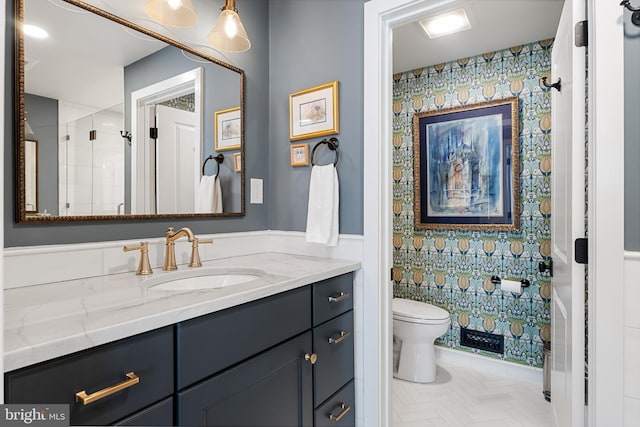 bathroom featuring vanity, a shower with door, toilet, and tile walls