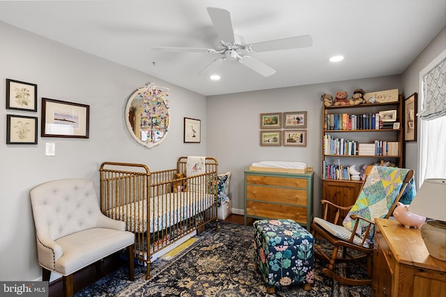 bedroom featuring ceiling fan and a nursery area