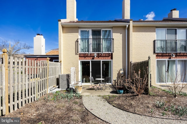 rear view of house with a patio area, a balcony, and central AC