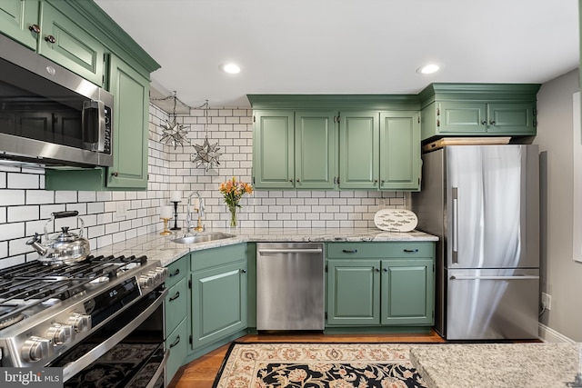 kitchen featuring green cabinets, decorative backsplash, sink, and stainless steel appliances