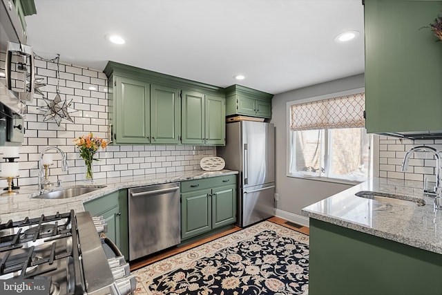 kitchen featuring tasteful backsplash, sink, appliances with stainless steel finishes, and green cabinetry