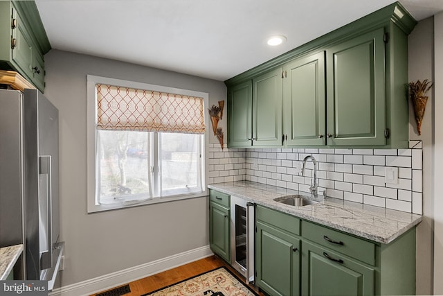 kitchen with stainless steel refrigerator with ice dispenser, backsplash, sink, light hardwood / wood-style flooring, and green cabinetry