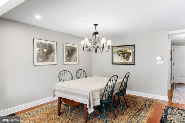 dining space featuring wood-type flooring and an inviting chandelier