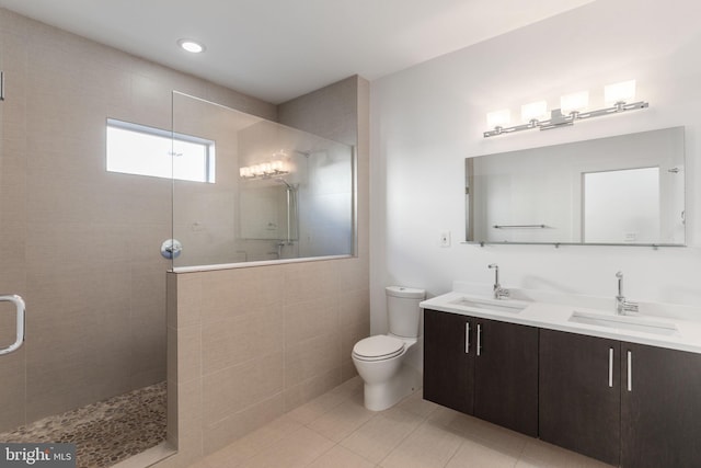 bathroom with a tile shower, tile patterned floors, vanity, and toilet