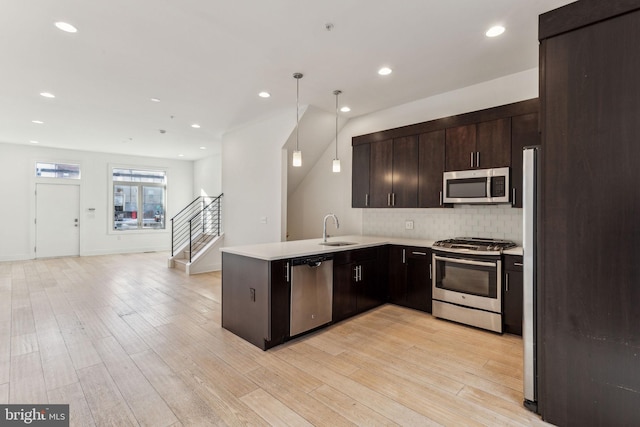 kitchen featuring sink, stainless steel appliances, backsplash, kitchen peninsula, and pendant lighting