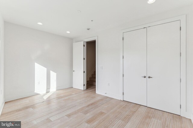 unfurnished bedroom with a closet and light hardwood / wood-style floors