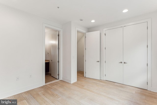 unfurnished bedroom featuring light wood-type flooring, a closet, and connected bathroom