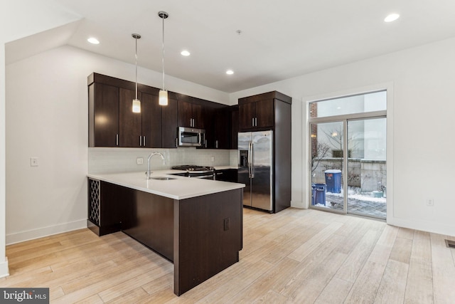 kitchen featuring sink, kitchen peninsula, hanging light fixtures, appliances with stainless steel finishes, and dark brown cabinetry