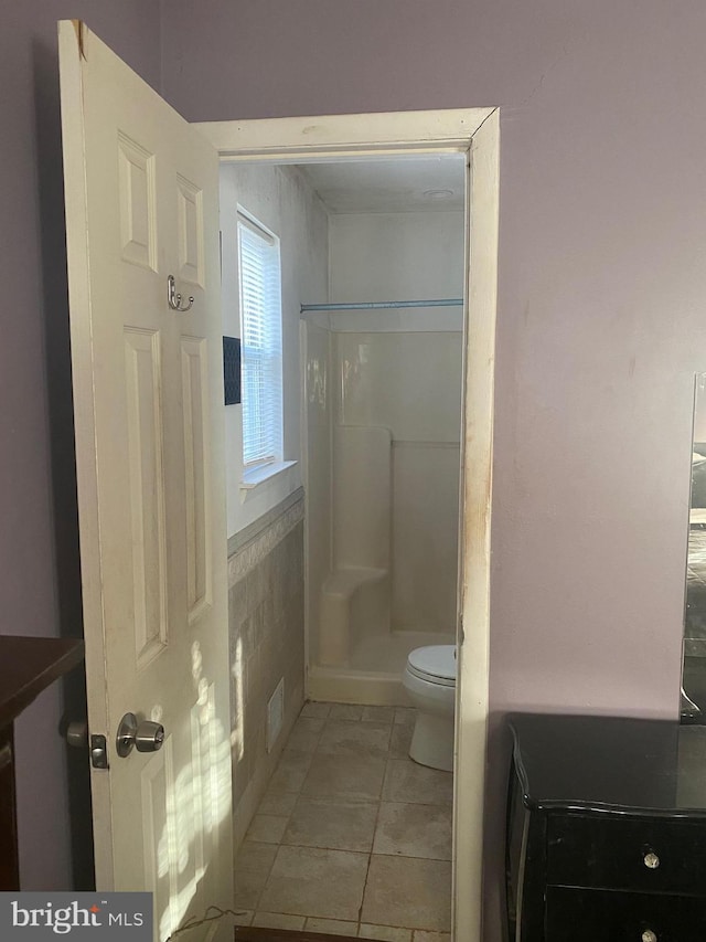 bathroom with a shower, tile patterned floors, and toilet