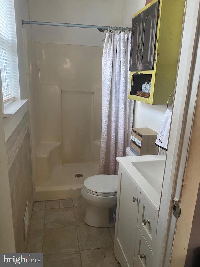 bathroom featuring toilet, vanity, tile patterned floors, and walk in shower