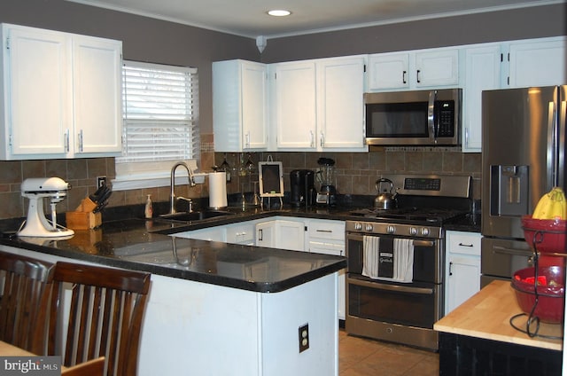 kitchen featuring kitchen peninsula, white cabinetry, sink, and appliances with stainless steel finishes