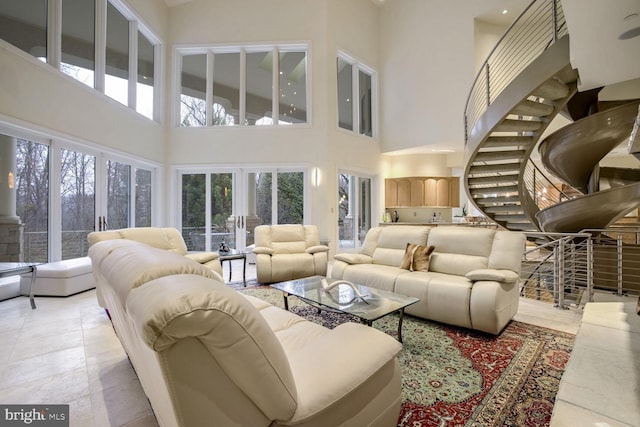 living room with a high ceiling, light tile patterned floors, and plenty of natural light