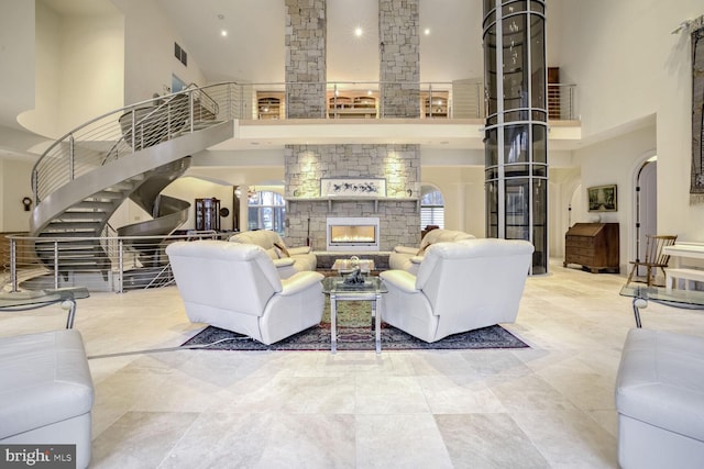 living room featuring a stone fireplace and a high ceiling