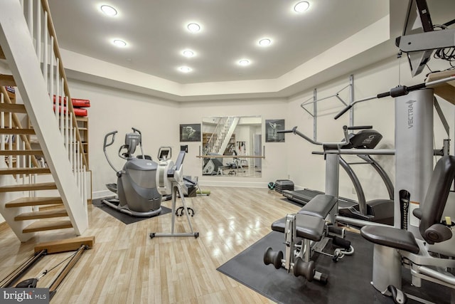 workout area featuring wood-type flooring and a raised ceiling