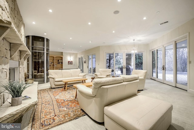 carpeted living room featuring an inviting chandelier, a fireplace, and french doors