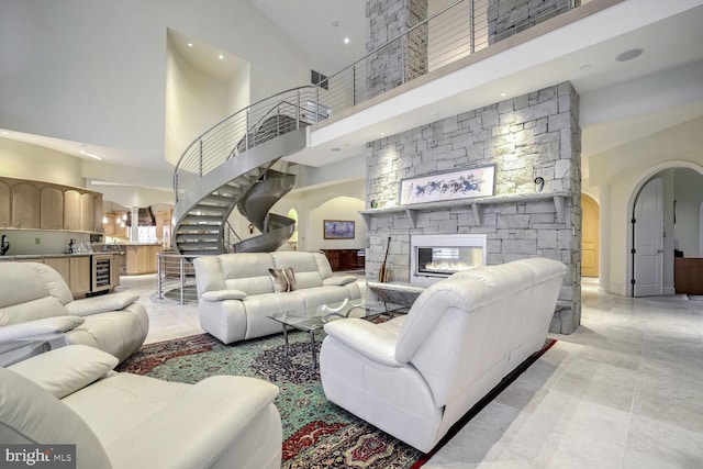 living room with wine cooler, a fireplace, and a high ceiling