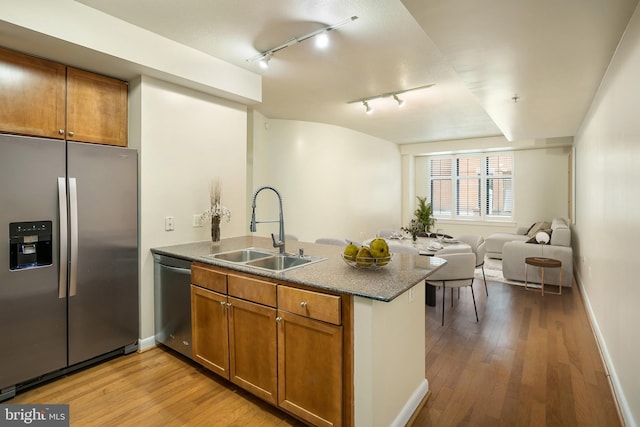 kitchen featuring sink, rail lighting, stainless steel appliances, kitchen peninsula, and light wood-type flooring