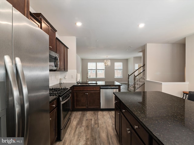 kitchen featuring sink, decorative light fixtures, dark stone countertops, stainless steel appliances, and decorative backsplash