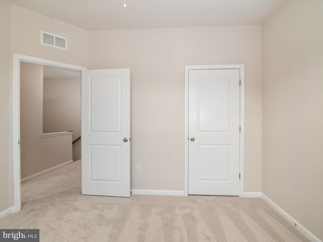 unfurnished bedroom featuring light carpet and a closet