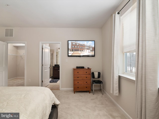 carpeted bedroom featuring a walk in closet, a closet, and ensuite bathroom