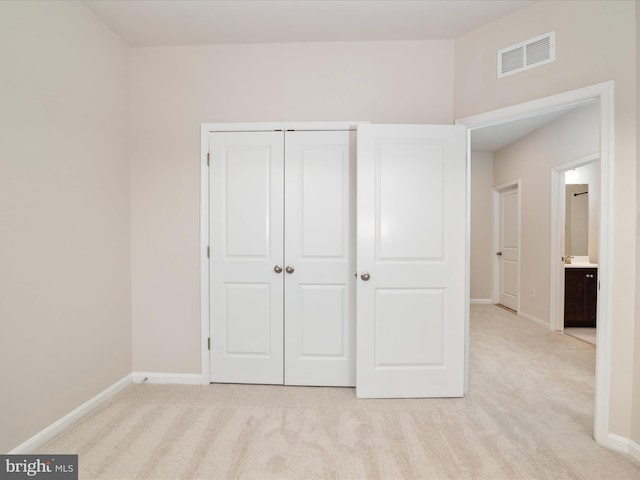 unfurnished bedroom with light carpet and a closet