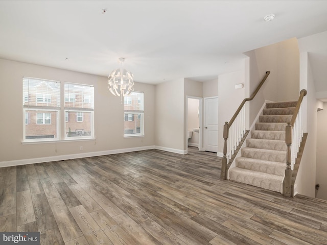 empty room with wood-type flooring and a chandelier