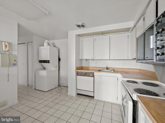 kitchen with light tile patterned flooring, sink, white appliances, stacked washer / dryer, and white cabinets