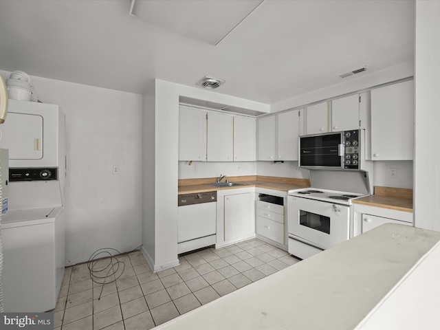 kitchen featuring stacked washer and dryer, white appliances, sink, and white cabinets