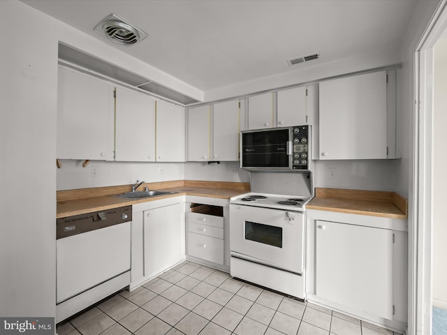 kitchen with sink, white appliances, light tile patterned floors, and white cabinets