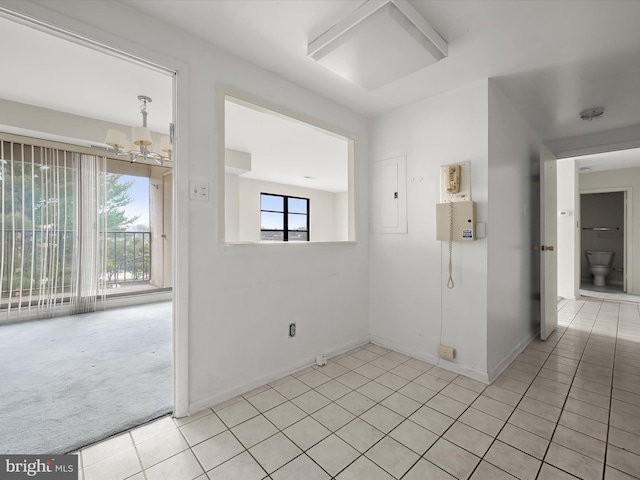 unfurnished room featuring light colored carpet, electric panel, and a chandelier