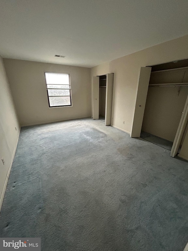 unfurnished bedroom with multiple closets and carpet floors